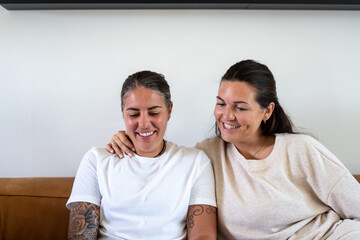 Fototapeta premium Adult lesbian couple use laptop on couch in living room