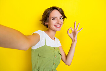 Closeup selfie photo of youngster woman toothy beaming smile showing okey sign recommend new brand isolated on yellow color background