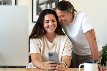 Adult lesbian couple use phone in home office