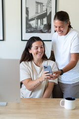 Obraz premium Adult lesbian couple use phone in home office