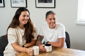 Adult lesbian couple have coffee together in dining room