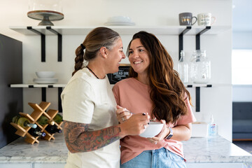 Naklejka premium Adult lesbian couple in kitchen share ice cream