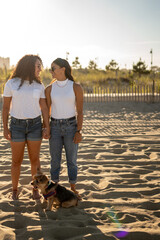 Hispanic lesbian couple stand on the beach holding hands