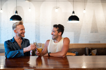 LGBTQ Friends sit at a bar with beer and champagne
