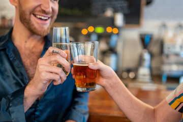 Fototapeta na wymiar Two LGBTQ friends cheers beer and champagne at a bar