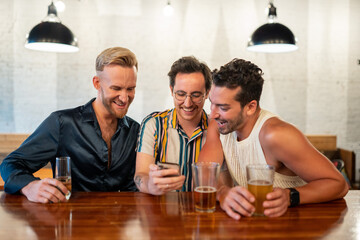 LGBTQ Friends sit at a bar and use a phone
