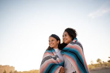 Hispanic lesbian couple uses blanket at beach