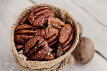 Close up of pecan nuts in brown sack on white wooden background