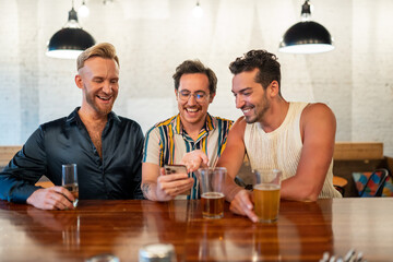 LGBTQ Friends sit at a bar and use a phone
