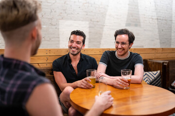 LGBTQ Friends sit at a bar with beer and champagne