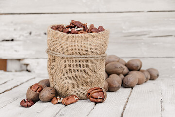 Pecan nuts in brown sack on white wood background ood photography