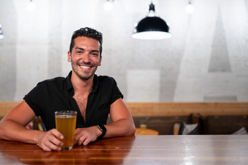 Gay man sits at a bar with beer