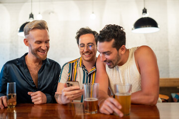 LGBTQ Friends sit at a bar and use a phone
