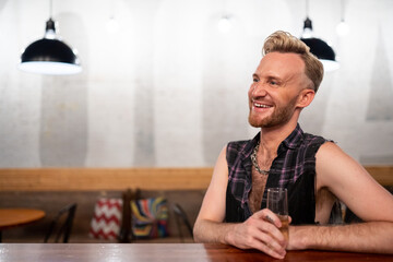 Gay man sits at a bar with champagne