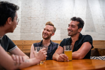 LGBTQ Friends sit at a bar with beer and champagne