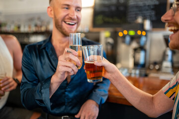 Two LGBTQ friends cheers beer and champagne at a bar