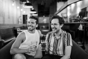 Two LGBTQ friends drink beer on a couch