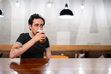 Bisexual man stands at a bar and drinks beer
