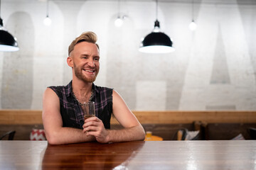 Gay man sits at a bar with champagne