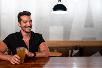 Gay man sits at a bar with beer