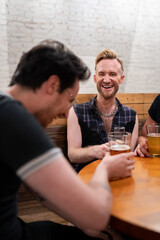 LGBTQ Friends sit at a bar with beer and champagne