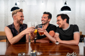 LGBTQ Friends sit at a bar with beer and champagne