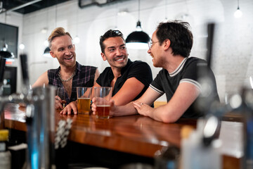 LGBTQ Friends sit at a bar with beer and champagne