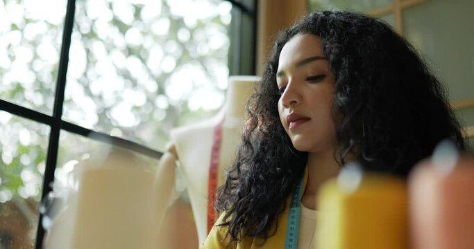 Handheld close up shot, Asian young female designer choose one of thread and selected the correct thread color for light blue fabric she was going to sew, Startup small business entrepreneur concept