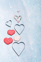 Gingerbread cookies and molds in shape of heart on bright aqua color background, flat lay, copy space