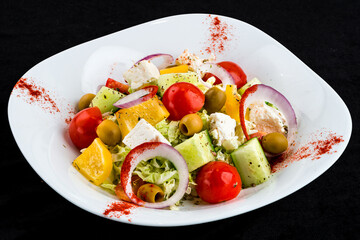 Greek salad of fresh cucumber, tomato, sweet pepper, lettuce, red onion, feta cheese and olives.