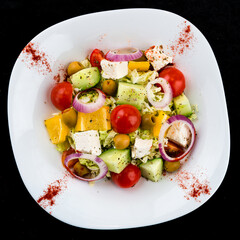 Fresh Greek salad of fresh cucumber, tomato, sweet pepper, lettuce, red onion, feta cheese and olives.