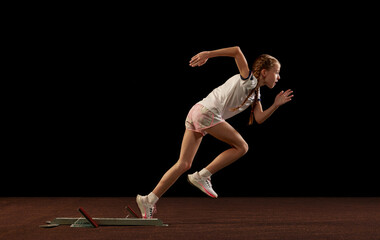 Focus on movement. Portrait of begginer athlete, runner training isolated on black studio background. Concept of action, motion, speed, healthy lifestyle.