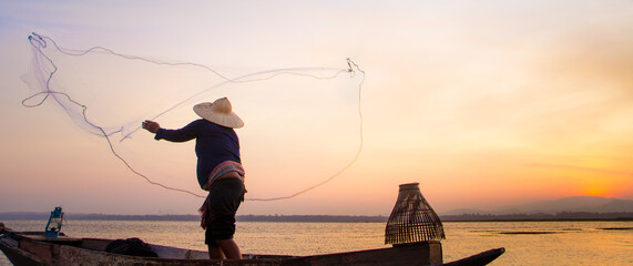 Silhouette of traditional fishermen throwing net fishing lake at sunrise time.(The casting people...