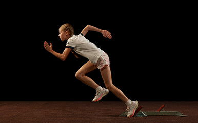 Focus on movement. Portrait of begginer athlete, runner training isolated on black studio...