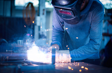Small industrial metal steel welder, welding skills, wearing mask and gloves for welding steel. For...