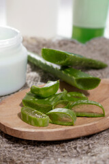 Obraz na płótnie Canvas Aloe Vera leaf cut into pieces on a wooden spoon, next to natural cosmetics. The concept of using natural cosmetic products with natural ingredients