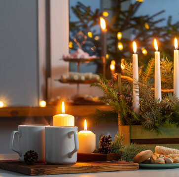 white cups with hot drink and christmas decorations at home