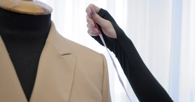 Closeup view tailor taking measures on mannequin