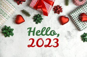 Fototapeta na wymiar Hello 2023 text surrounded with ornamnet,gifts,bows,etc in red,white and gree. Traditional flat lay