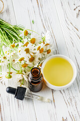 aromatic chamomile essential oil on a white wooden rustic background
