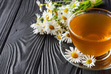 aromatic hot chamomile tea on a black rustic wooden background