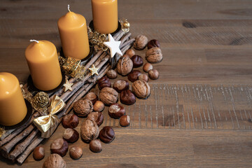 Candlestick with four candles and a scattering of nuts on a beautiful aged wooden table
