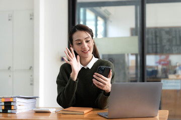 Asian businesswoman in formal suit in office happy and cheerful during using smartphone and working