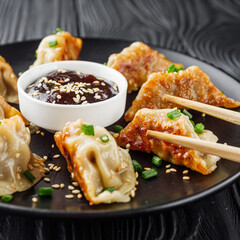 delicious fried gyoza dumplings on a black plate