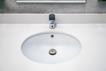 a round sink for washing hands and an automatic faucet for water in a public toilet