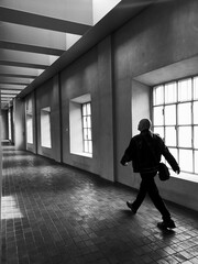 Man walks through a corridor illuminated by bright windows. Modern space