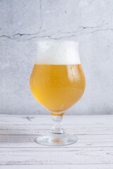 copa de cerveza rubia bien fria con espuma recien  ervida
