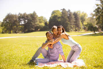 Happy young family with cute little daughter having fun in the park on a sunny day