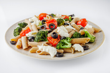 delicious penne wheat pasta with tomatoes, broccoli and mozzarella on a white background