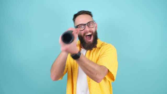 Crazy emotions. Young funny hipster tourist looking through a spyglass and considering the sights isolated on studio background. Looking for discounts, sale, seasonal sales. Colorful summer concept.